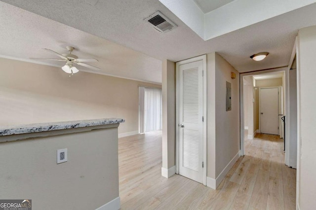 hall featuring light wood-type flooring and a textured ceiling