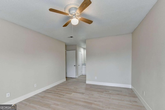 spare room with a textured ceiling, ceiling fan, and light hardwood / wood-style flooring