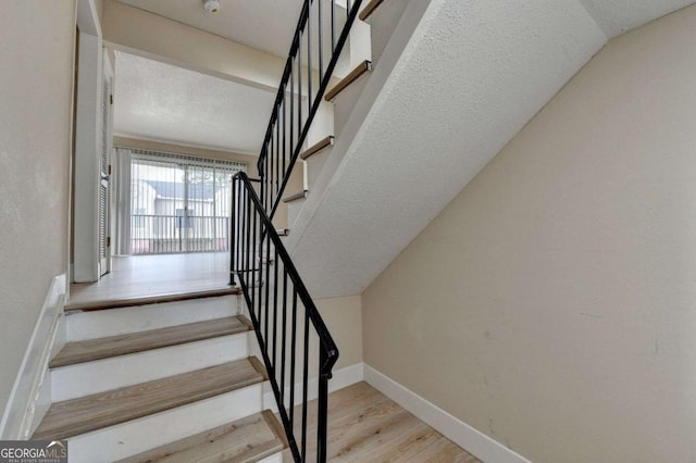 staircase featuring vaulted ceiling and wood-type flooring