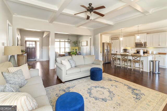 living room with crown molding, dark wood-type flooring, beamed ceiling, and ceiling fan with notable chandelier