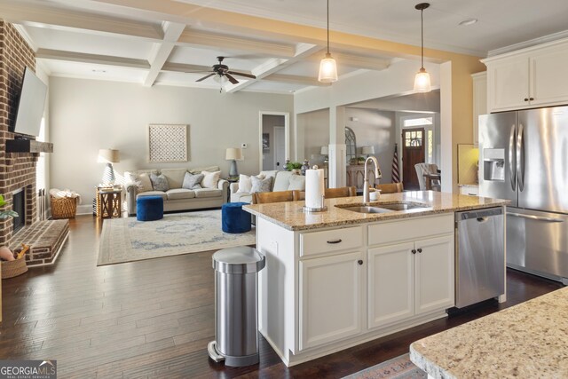 kitchen with decorative light fixtures, dishwasher, sink, a kitchen island with sink, and light stone countertops