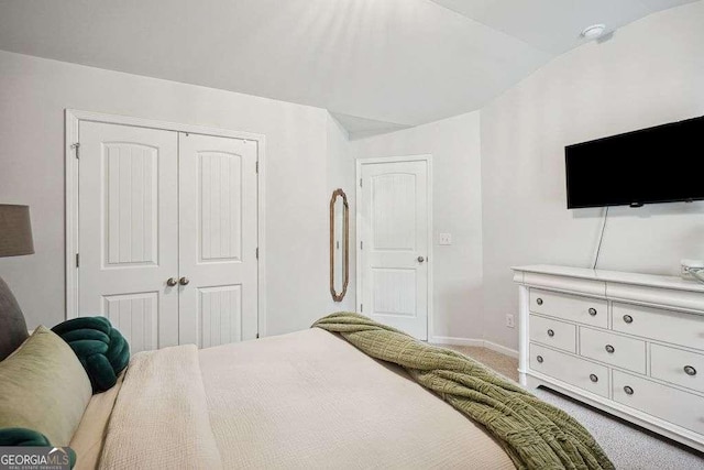 carpeted bedroom featuring a closet and vaulted ceiling