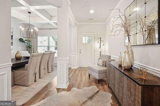 entryway featuring beam ceiling, crown molding, coffered ceiling, light wood-type flooring, and ornate columns