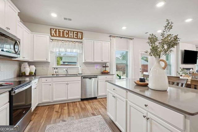 kitchen featuring white cabinetry, light hardwood / wood-style floors, stainless steel appliances, backsplash, and sink