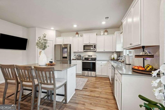 kitchen with backsplash, sink, white cabinetry, a breakfast bar area, and stainless steel appliances