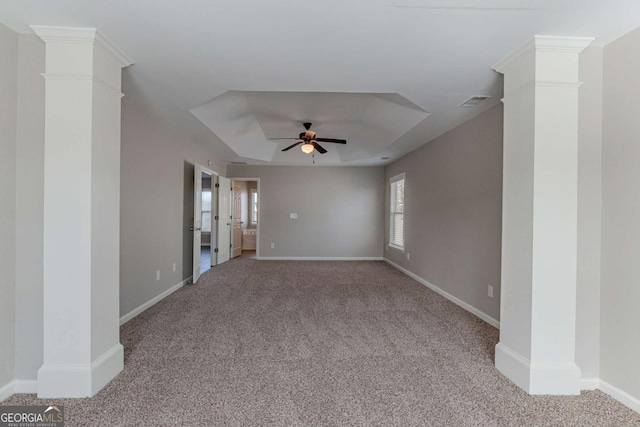 empty room featuring ceiling fan, light carpet, decorative columns, and a raised ceiling