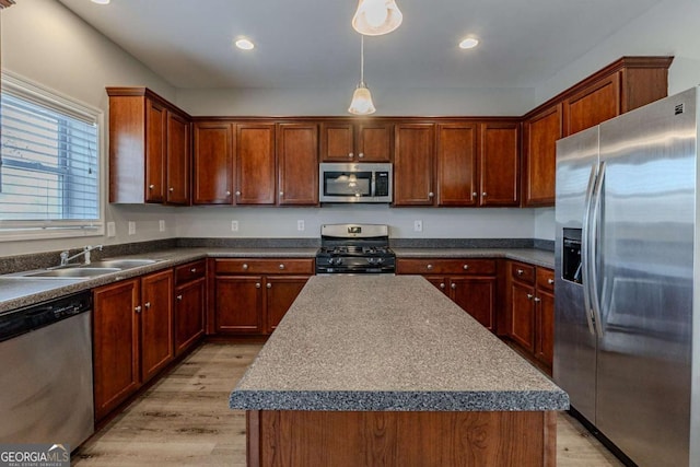 kitchen featuring stainless steel appliances, light hardwood / wood-style flooring, a center island, and sink