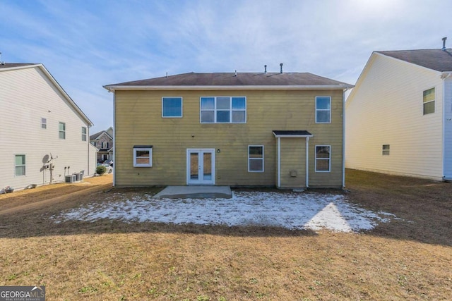 back of property with central AC unit, french doors, and a lawn