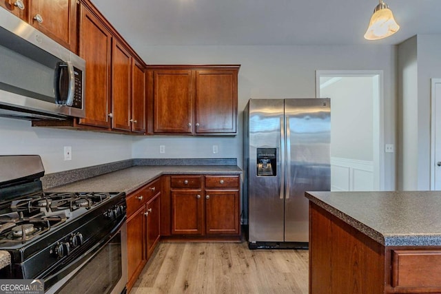 kitchen with hanging light fixtures, stainless steel appliances, and light hardwood / wood-style flooring