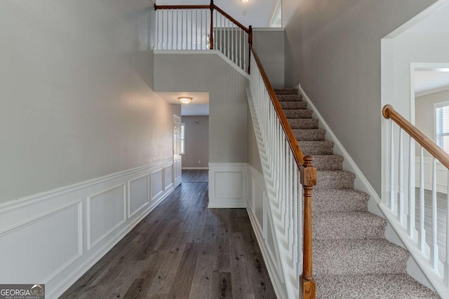 stairway featuring wood-type flooring and a high ceiling