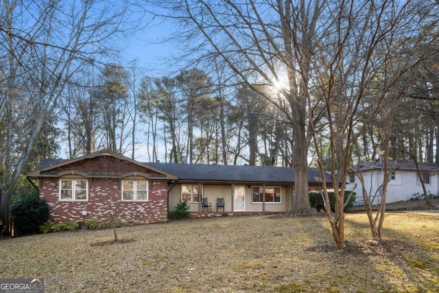 ranch-style home featuring covered porch and a front yard