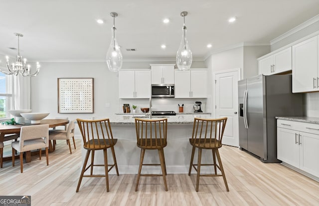 kitchen with appliances with stainless steel finishes, an island with sink, white cabinets, and light stone countertops