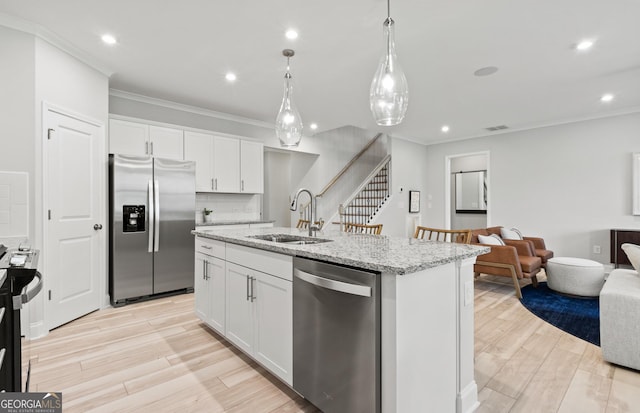 kitchen with sink, white cabinetry, stainless steel appliances, and an island with sink