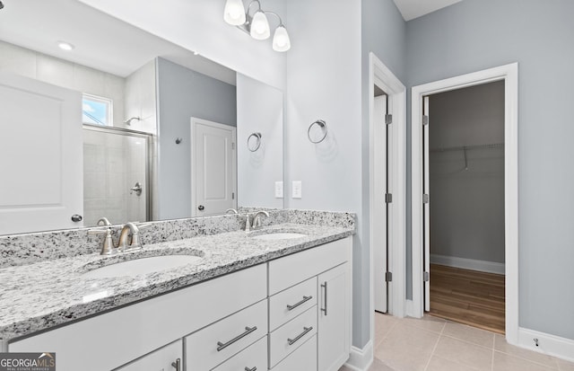 bathroom with walk in shower, vanity, and tile patterned flooring