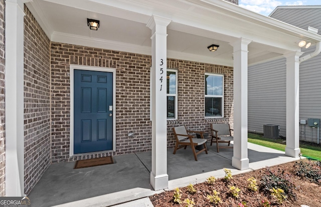 view of exterior entry with covered porch and central air condition unit