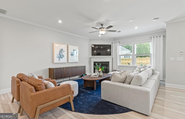 living room featuring ceiling fan, ornamental molding, and light hardwood / wood-style flooring