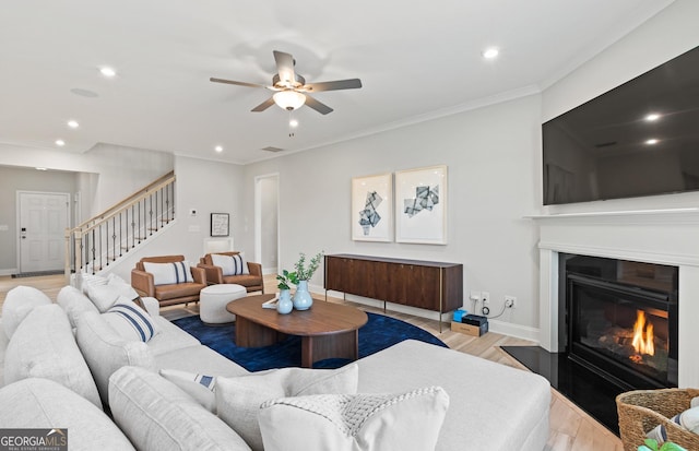 living room featuring light wood-type flooring, ceiling fan, and crown molding