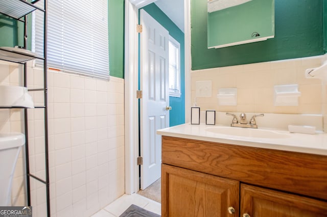 bathroom with tile walls, vanity, toilet, and tile patterned floors