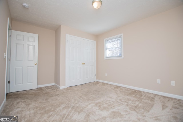 unfurnished bedroom with light carpet, a closet, and a textured ceiling