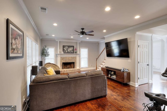 living room with ceiling fan, dark wood-type flooring, ornamental molding, and a brick fireplace