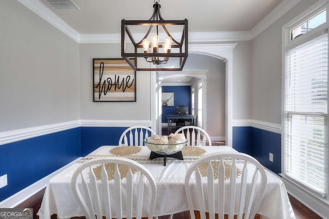 dining area with a wealth of natural light, dark hardwood / wood-style flooring, ornamental molding, and a chandelier