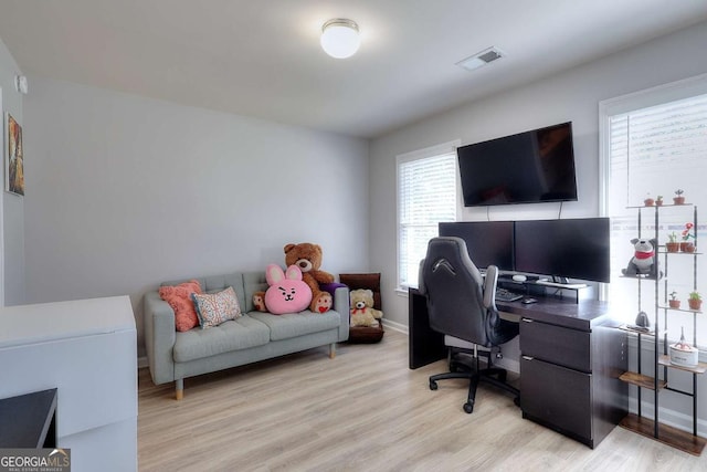 home office with a wealth of natural light and light hardwood / wood-style floors