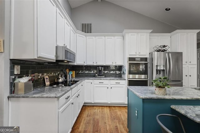 kitchen with appliances with stainless steel finishes, decorative backsplash, white cabinetry, and light stone counters