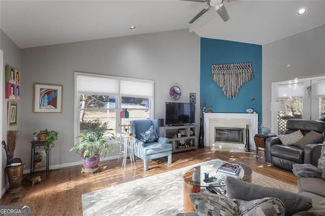 living room featuring hardwood / wood-style flooring, ceiling fan, and vaulted ceiling