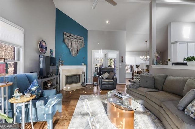 living room featuring high vaulted ceiling, a wealth of natural light, ceiling fan with notable chandelier, and hardwood / wood-style floors