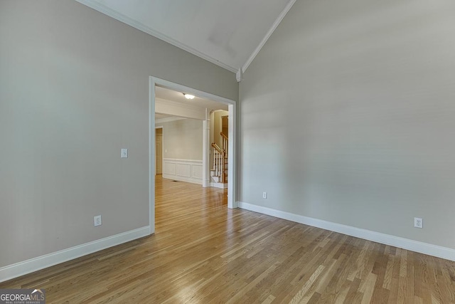 spare room featuring vaulted ceiling, crown molding, and light hardwood / wood-style floors