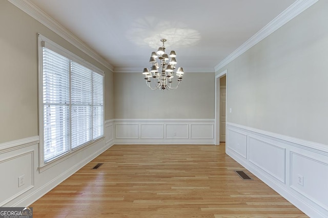 unfurnished dining area featuring an inviting chandelier, ornamental molding, and light hardwood / wood-style flooring