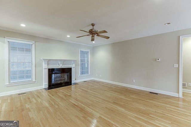 unfurnished living room featuring a premium fireplace, ornamental molding, light hardwood / wood-style flooring, and ceiling fan