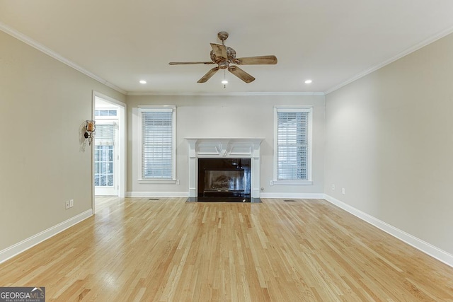 unfurnished living room featuring ceiling fan, a premium fireplace, ornamental molding, and light hardwood / wood-style floors