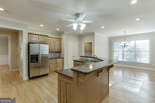 kitchen featuring tasteful backsplash, pendant lighting, a center island, sink, and stainless steel fridge