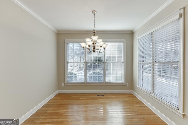 unfurnished dining area with wood-type flooring, crown molding, and a notable chandelier