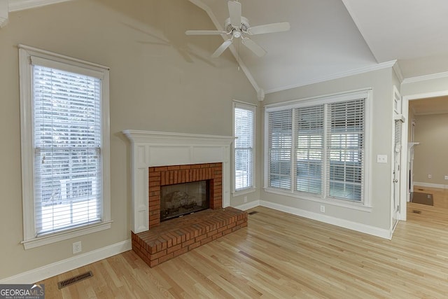 unfurnished living room with a healthy amount of sunlight, light hardwood / wood-style floors, ceiling fan, vaulted ceiling, and a brick fireplace