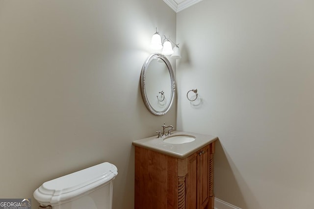 bathroom with toilet, vanity, and crown molding