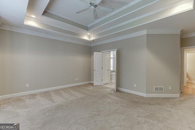 carpeted spare room with ceiling fan, crown molding, and a raised ceiling