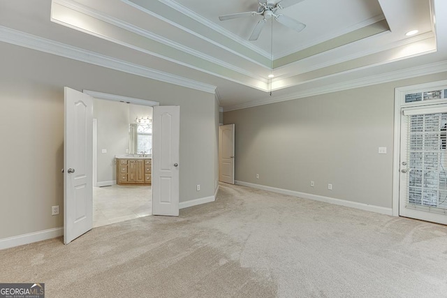 empty room featuring ceiling fan, light colored carpet, a tray ceiling, and ornamental molding