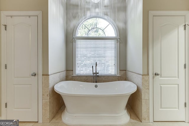 bathroom featuring tile walls, tile patterned floors, a wealth of natural light, and a bath