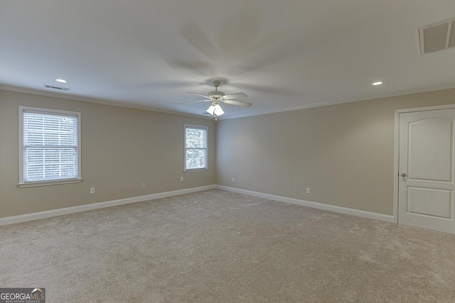 spare room featuring ceiling fan, plenty of natural light, light colored carpet, and ornamental molding