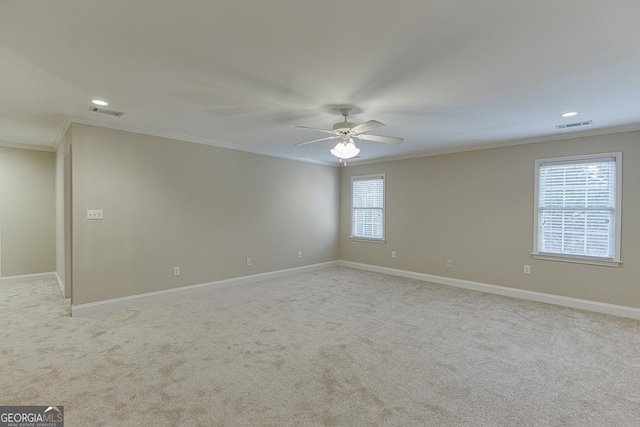 spare room with ceiling fan, light colored carpet, and crown molding