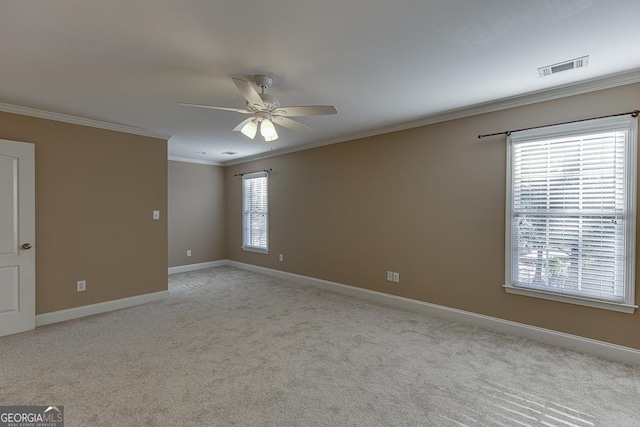 empty room featuring ceiling fan, ornamental molding, a healthy amount of sunlight, and light colored carpet