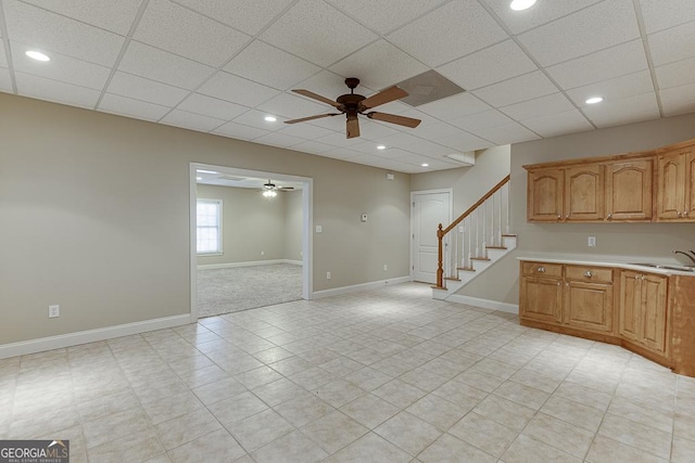 unfurnished living room featuring ceiling fan, a paneled ceiling, and sink