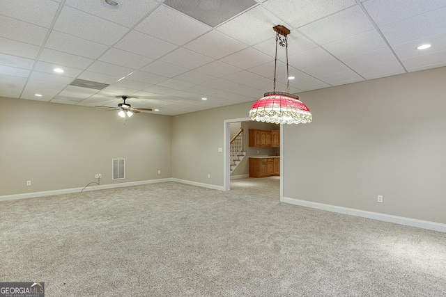 carpeted spare room with ceiling fan and a drop ceiling