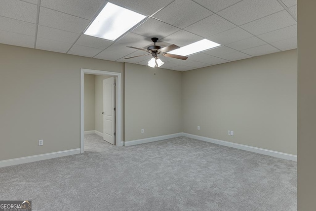 carpeted empty room with ceiling fan and a drop ceiling