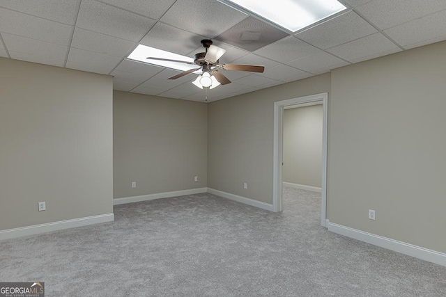 empty room with ceiling fan, light colored carpet, and a drop ceiling