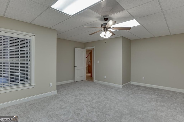 carpeted spare room with ceiling fan and a drop ceiling