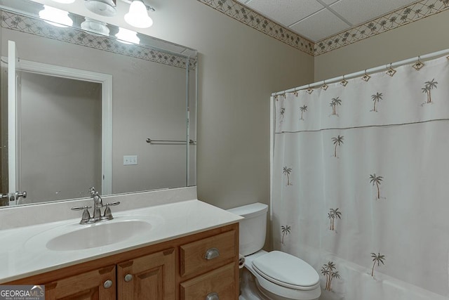 full bathroom with toilet, shower / bath combo, a drop ceiling, and vanity