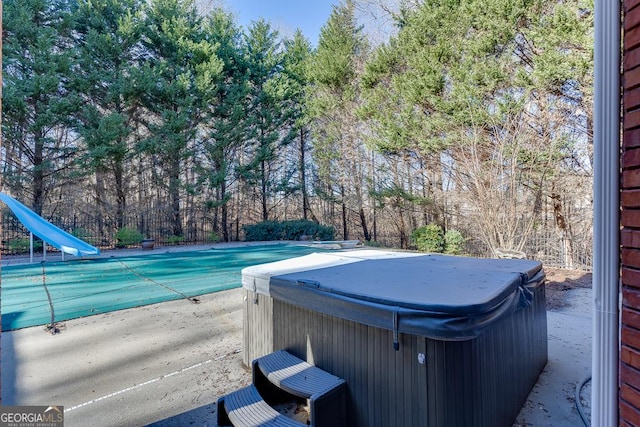 view of swimming pool with a hot tub and a water slide